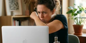 Femme qui tousse en vapotant devant son ordinateur - Sensibilité au propylène glycol